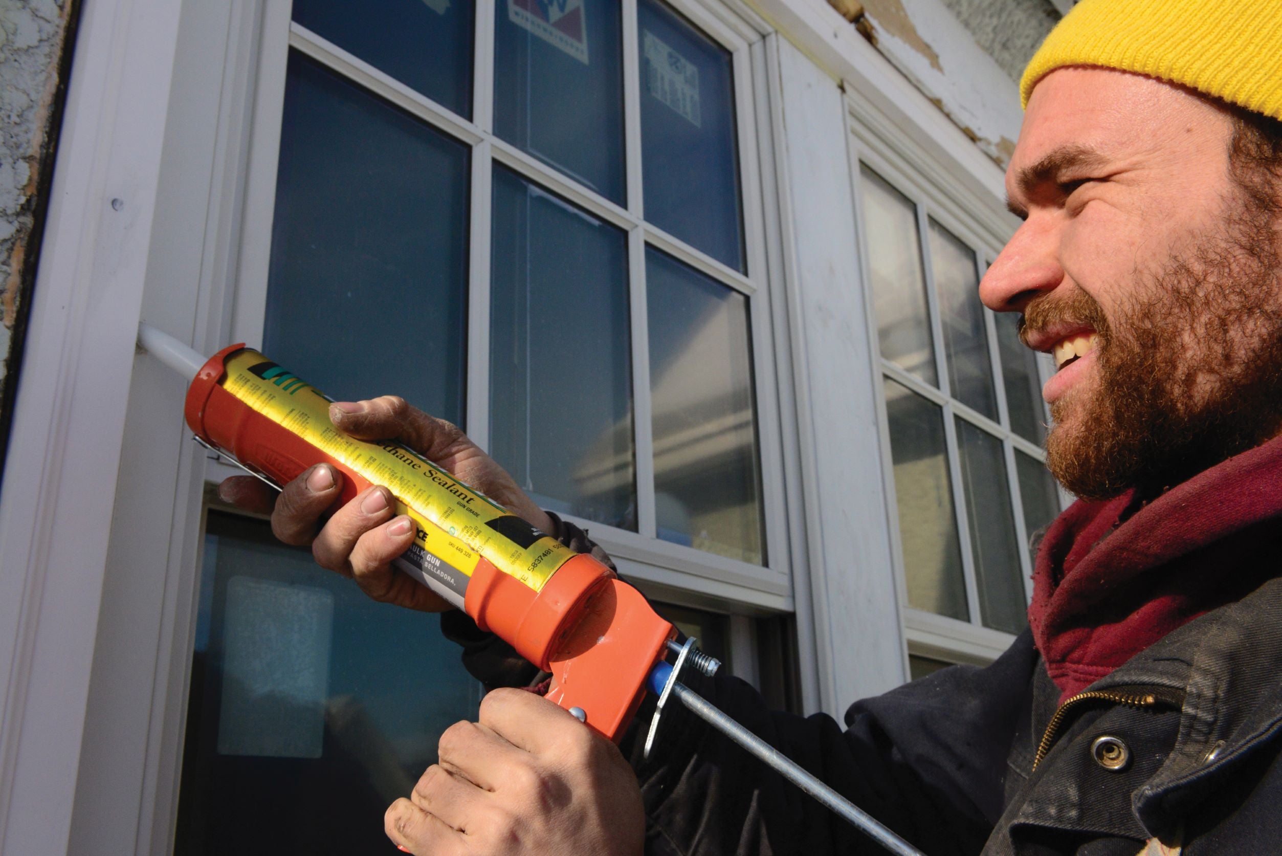 Man caulking outside of house.
